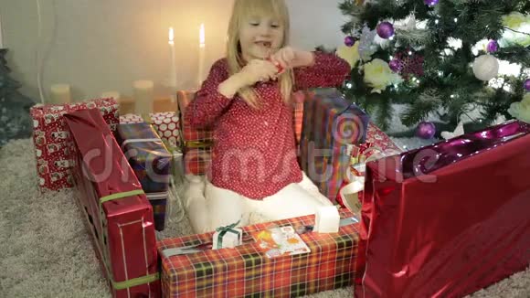 小女孩在圣诞礼物上玩红口香糖视频的预览图