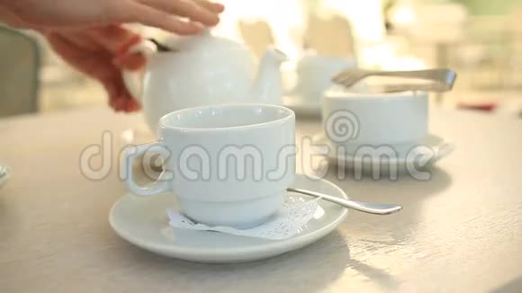 有人把白瓷茶壶里的茶倒进白杯子里视频的预览图