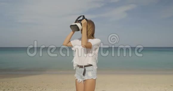 海滩上戴虚拟现实眼镜的年轻女子视频的预览图
