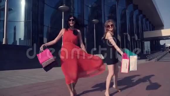 漂亮的年轻女孩对成功的购物很满意手拿购物包的女朋友跳舞微笑视频的预览图