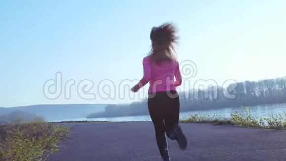 活泼的女孩在日出或日落时沿着河岸慢跑运动女性的健康生活方式观念视频的预览图