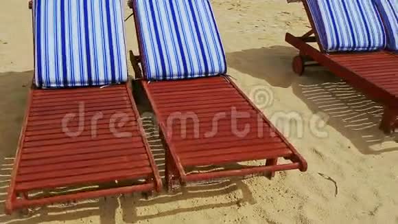 海滩上有带条纹床垫的紧身棕色躺椅视频的预览图