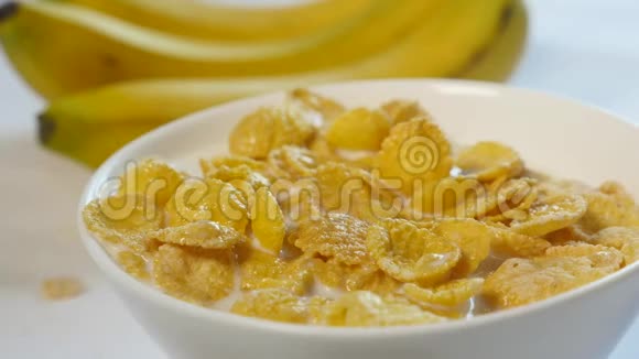 玉米片和牛奶放在碗里香蕉碎片落在这顿美味早餐的顶部特写镜头视频的预览图