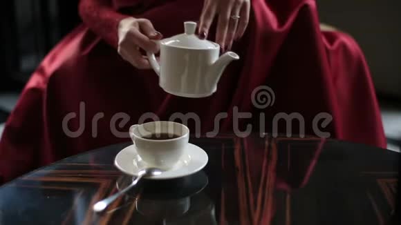 特写看着手中的红衣女子将茶倒进杯子里喝着咖啡厅的位置视频的预览图