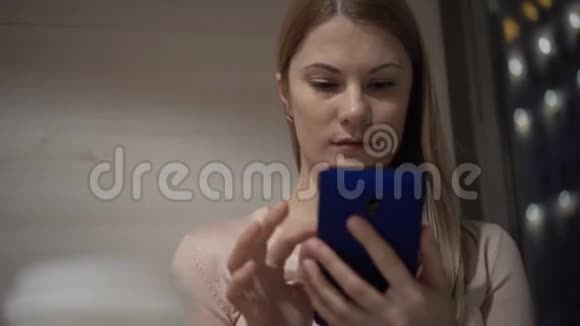 漂亮的年轻女人在咖啡馆里用她的智能手机浏览互联网与朋友交流视频的预览图