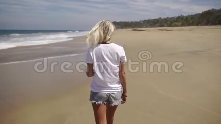 年轻女子走在沙滩上看着镜头微笑视频的预览图