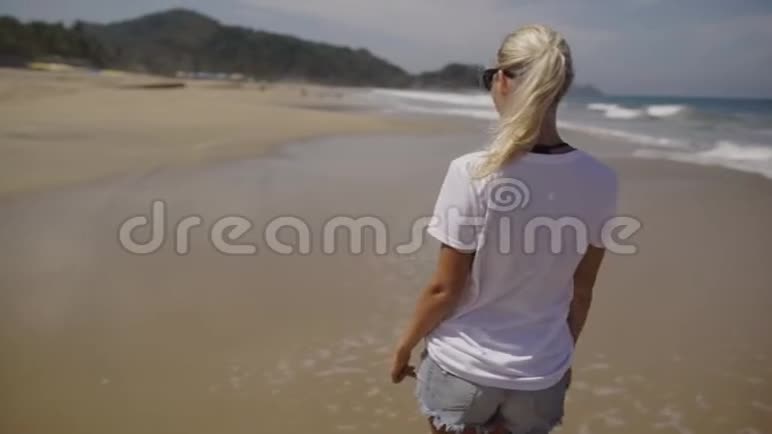 年轻女子走在沙滩上看着镜头微笑视频的预览图
