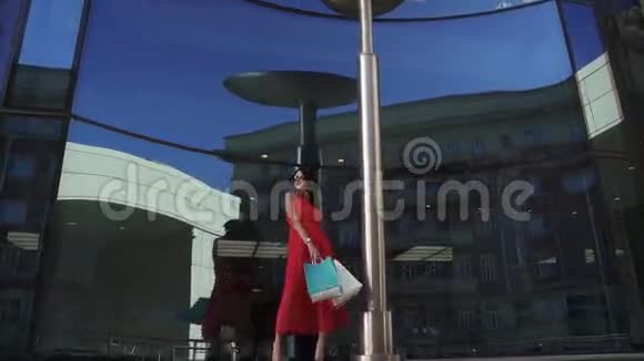 漂亮的模特手里拿着购物袋在现代建筑的背景下摆姿势年轻漂亮的女孩视频的预览图