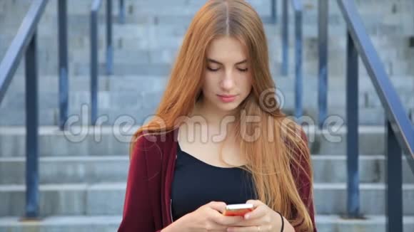日出时美丽优雅的长发美女在城市的智能手机上发短信视频的预览图