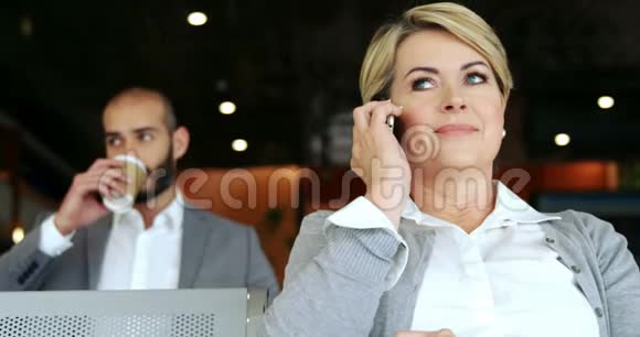 女人在用手机说话男人在后台喝咖啡视频的预览图