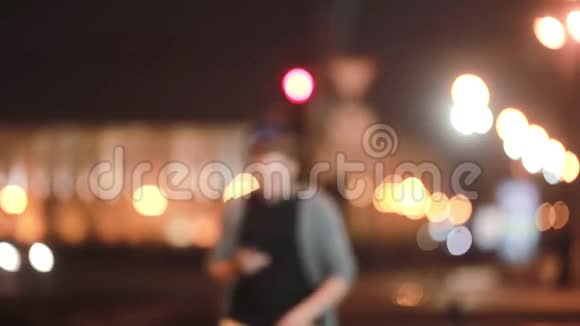 英俊的男人走路微笑使用他的智能手机然后离开街道上的城市灯光模糊现代技术视频的预览图