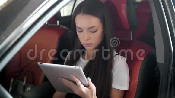 年轻漂亮的女人系好安全带坐在汽车后座上视频的预览图