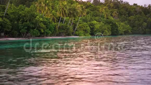 西巴布亚Gam岛RajaAmpat海滩上的一个寄宿小屋附近的水面上反射着日落光线视频的预览图
