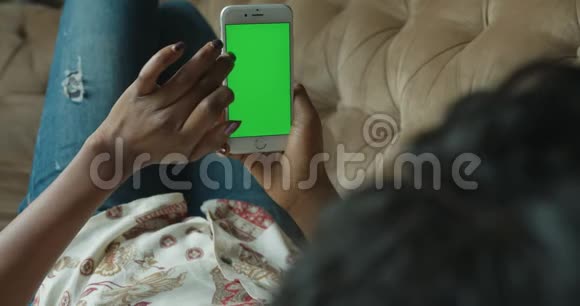 后景特写非洲裔美国妇女无脸手机绿屏冲浪网聊天躺沙发放松4k视频的预览图