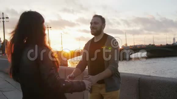 快乐的一对情侣在城市里太阳落山的时候拥抱和旋转桥河路慢莫视频的预览图