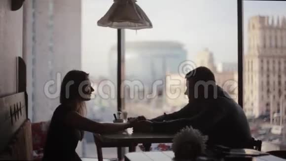 一对情侣坐在桌旁约会的剪影高楼大厦咖啡厅窗外的城市街景不错视频的预览图
