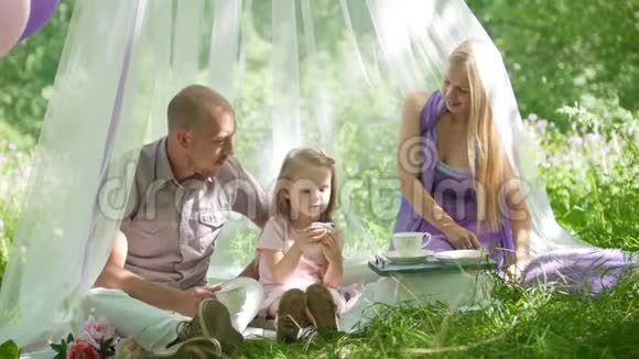 一家人在公园里休息爸爸妈妈和女儿吃早餐视频的预览图