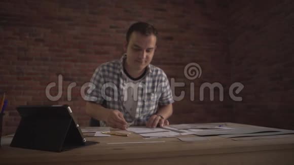 一位细心工作的年轻人把注意力集中在木桌上的纸工商业项目上视频的预览图