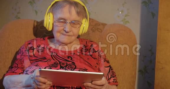 带平板电脑和耳机的现代祖母视频的预览图