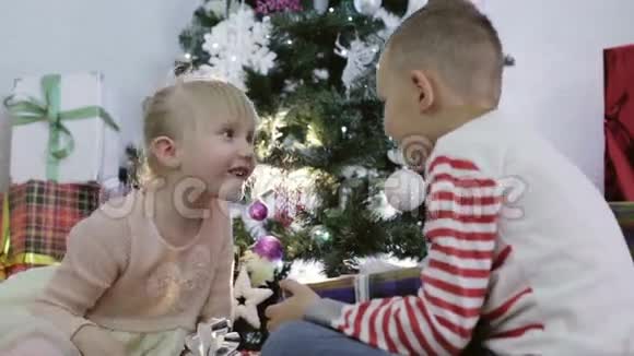男孩和女孩在圣诞树附近谈笑风生视频的预览图