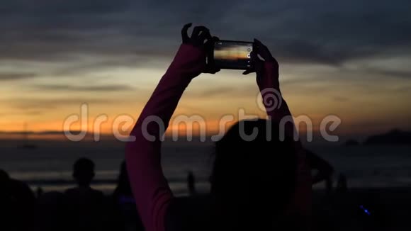 在海滩用电话拍照的女人剪影视频的预览图