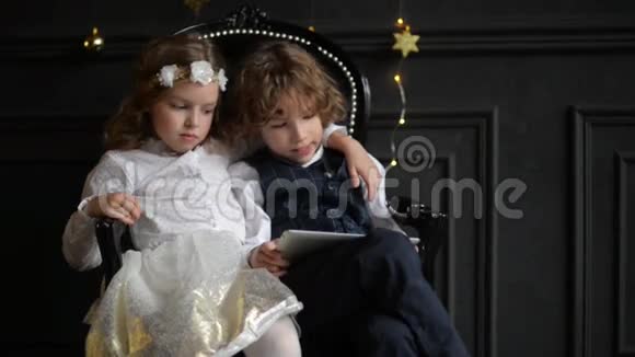 可爱的女孩和她的哥哥一起玩数字平板电脑孩子们在笔记本电脑上玩拥抱圣诞快乐视频的预览图