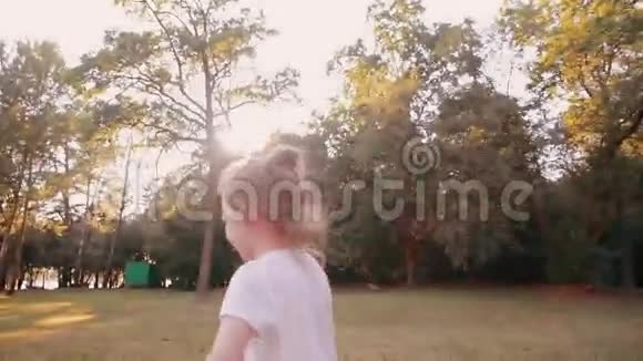 快乐的小女孩在大自然的镜头前吹吻日落的光阳光透过树木照耀慢节奏视频的预览图