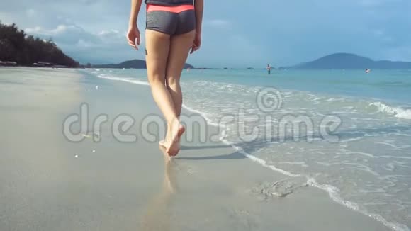 日落时光着脚在海滩上散步的女人女人在海边的沙滩上散步视频的预览图