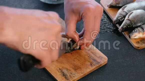 人把鲤鱼的鳍切在木板上煮鱼把手举起来视频的预览图