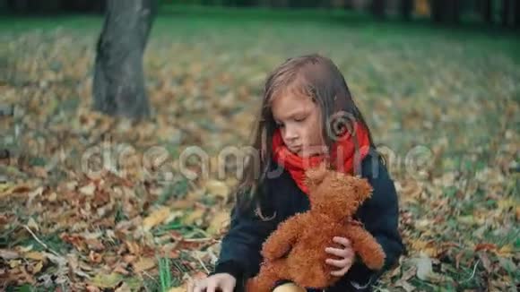 可爱可爱的小女孩在神奇的秋季公园玩她的玩具熊4k视频的预览图