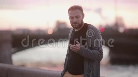 帅哥用智能手机看着镜头站在码头上用闪光灯拍照现代技术视频的预览图