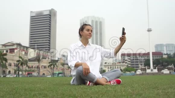 吉隆坡的游客在草地上拍照和自拍视频的预览图