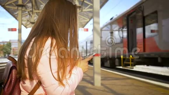 车站的年轻漂亮女人通过智能手机在线订购门票带眼镜长发粉色夹克视频的预览图