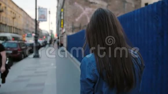 女士走在蓝色栅栏附近的街道上长发女人在电话里说话的背景慢莫稳定射击视频的预览图