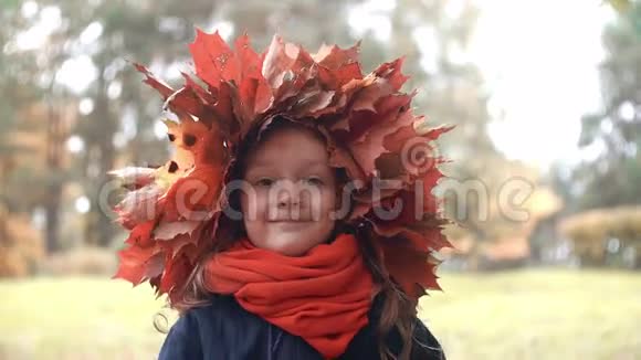 4k张可爱的小女孩的特写照片她戴着秋枫叶的花环露出一张滑稽的脸视频的预览图
