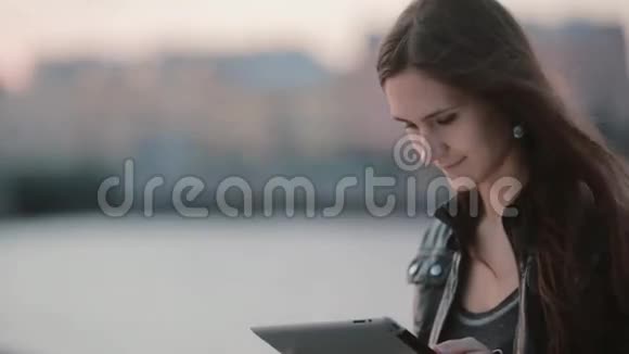 有魅力的女人用平板电脑漂亮的女孩看着她的平板电脑微笑风吹着她的头发现代技术视频的预览图