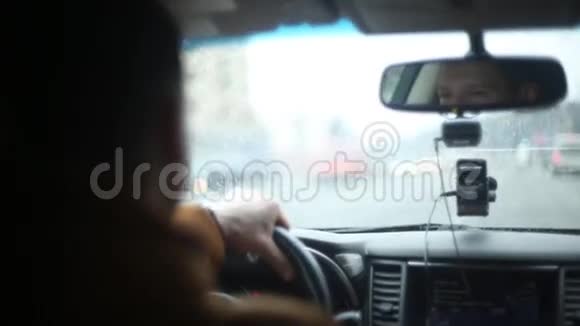雨天开车时笑脸的特写左手放在方向盘上繁忙的道路开车旅行视频的预览图