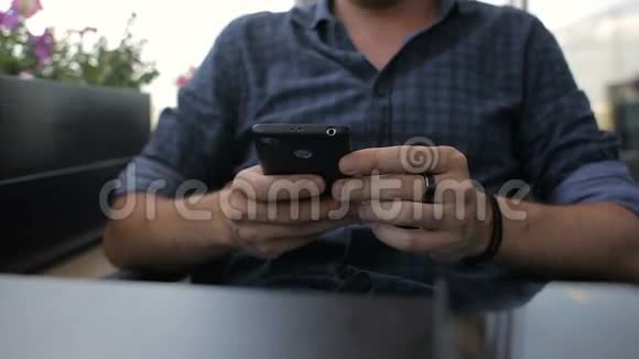 一个人在咖啡馆的智能手机上收到短信视频的预览图