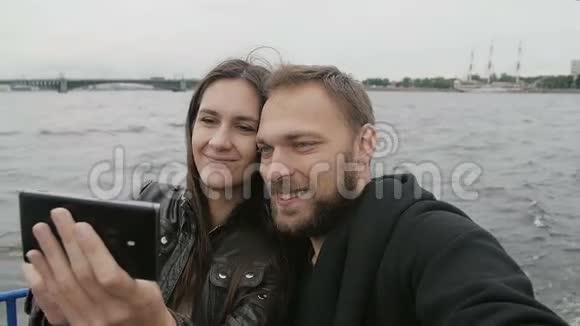 微笑美丽的夫妇使用智能手机自拍在河流巴士圣彼得堡观光桥慢游视频的预览图