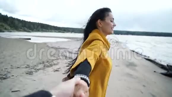 女人牵着男人的手在海滩上微笑视频的预览图