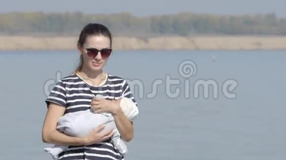 年轻母亲和婴儿在海岸散步的肖像视频的预览图