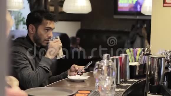 一个年轻人在咖啡馆里喝咖啡用移动设备视频的预览图