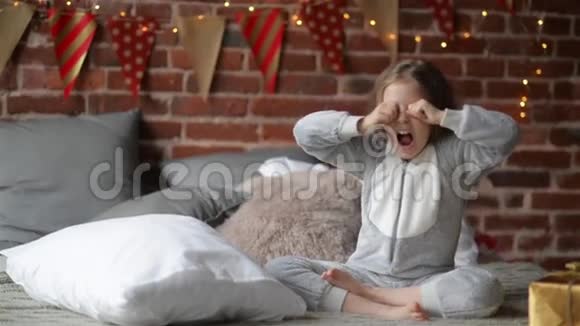 在节日的早晨小女孩穿着温暖的圣诞睡衣在床上醒来带着礼物圣诞快乐视频的预览图