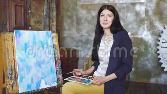 年轻的女艺术家用水彩画画图画微笑着看着镜头视频的预览图