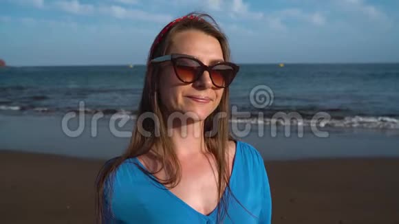 一个女人穿着漂亮的蓝色裙子在黑色火山海滩上的肖像视频的预览图