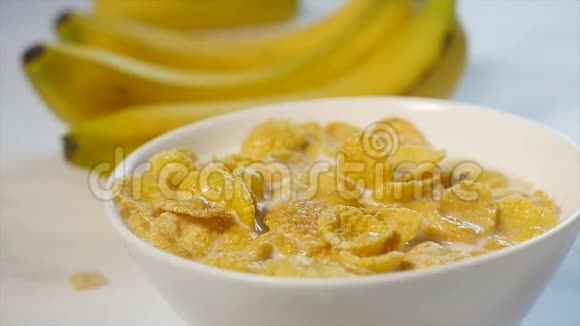 玉米片和牛奶放在碗里香蕉碎片落在这顿美味早餐的顶部特写镜头视频的预览图