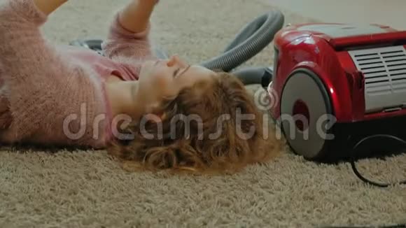 快乐的年轻女子或家庭主妇带着吸尘器躺在地板上用电话玩得开心玩得开心视频的预览图