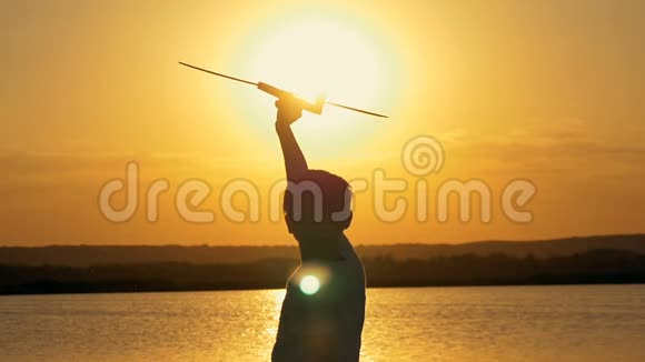 快乐的孩子在一个橙色的天空和湖泊的背景下在夏天日落玩玩具飞机视频的预览图
