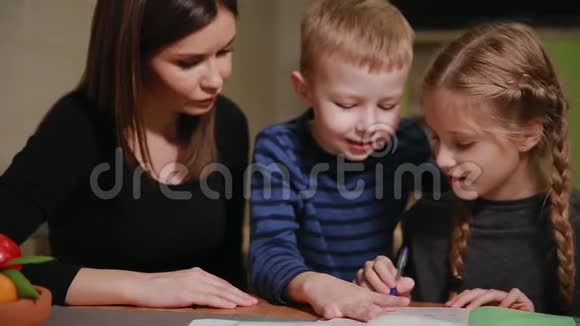 母女俩在做学校作业一个小男孩在看哥哥帮忙做作业视频的预览图