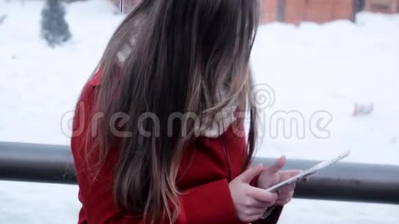 年轻女孩坐在公共汽车站看平板电脑视频的预览图